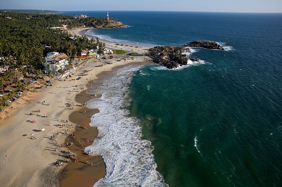 Panoramic sea view of Kovalam Beach in Kerala with the Arabian Sea, golden coastline, coconut palms and iconic Vizhinjam Lighthouse.