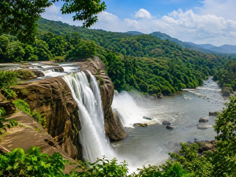 Athirappilly Waterfalls in Thrissur Kerala cascading over rocky cliffs surrounded by lush green Western Ghats forest.